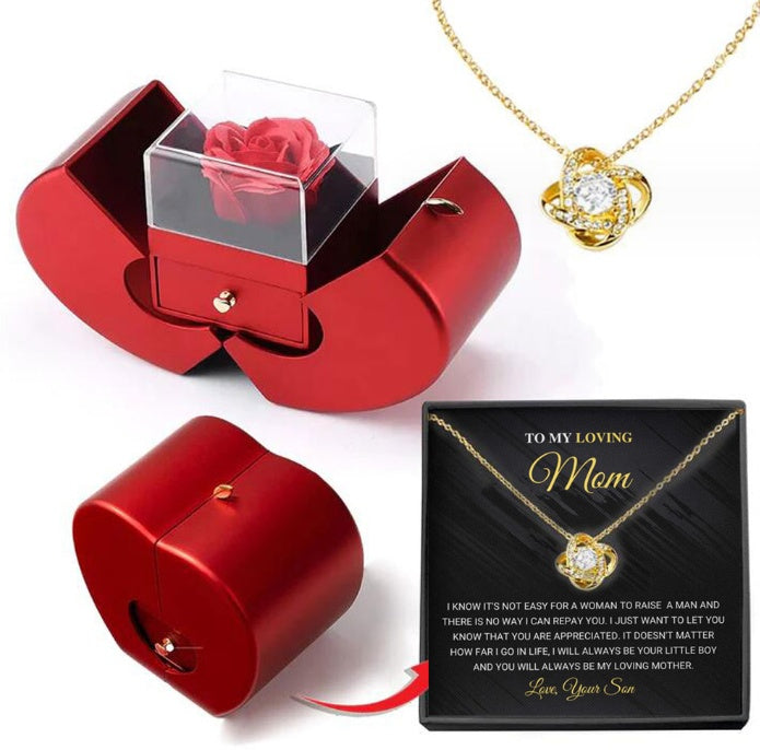 Red jewelry box with a rose, gold necklace, and black card for 'Mom' on a white background