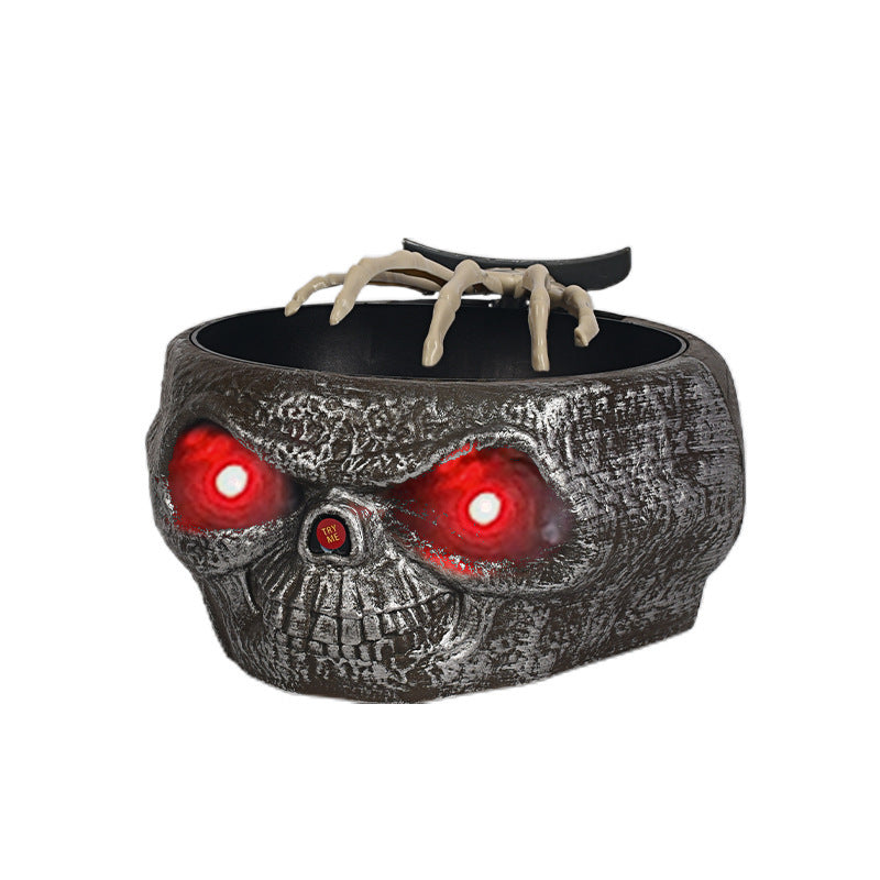 Skull-shaped container with glowing red eyes and clawed hand on a white background