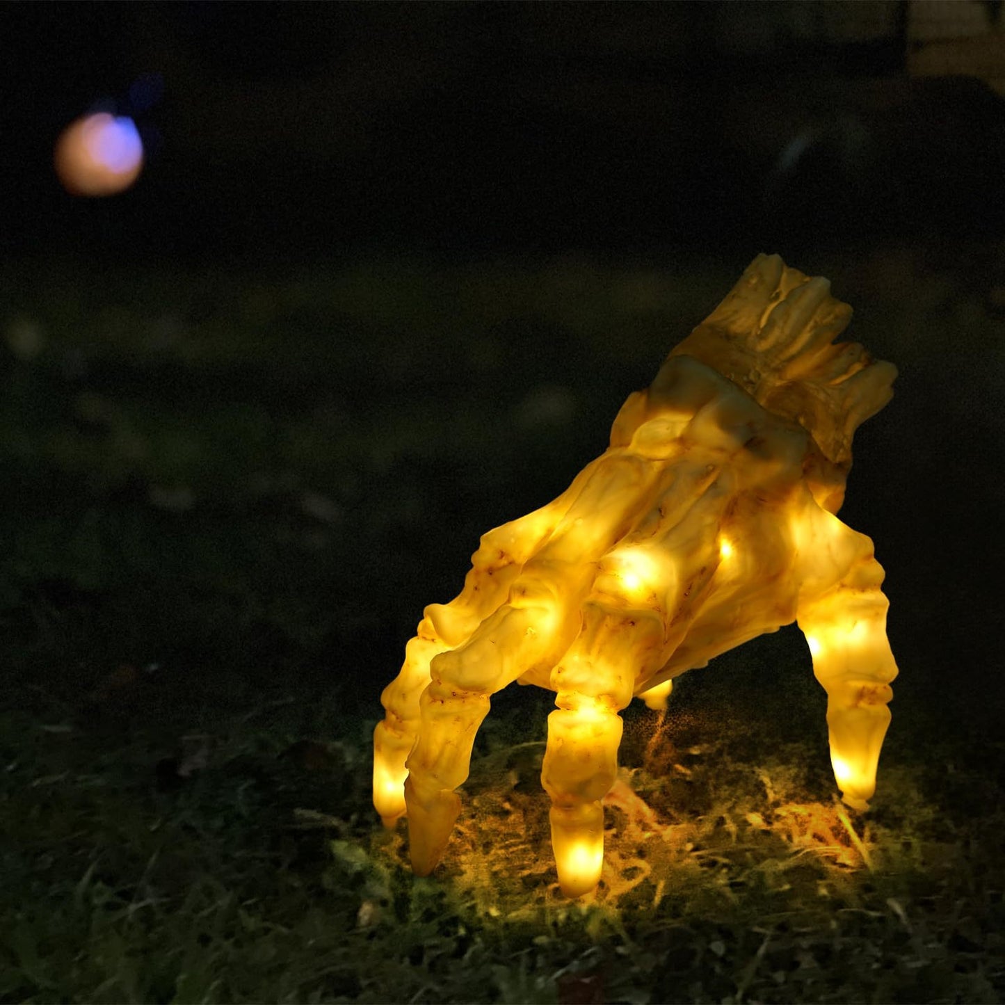 Decorative light sculpture of a deer on grass at night