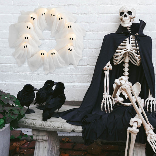 Skeleton in a black cape with crows and a ghostly wreath on a white brick wall.