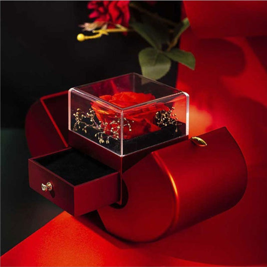 Red rose in a transparent box inside an open red heart-shaped box on a dark background