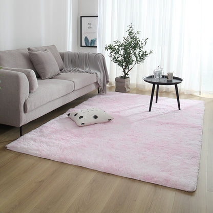 Living room with a pink rug, gray sofa, and small table.