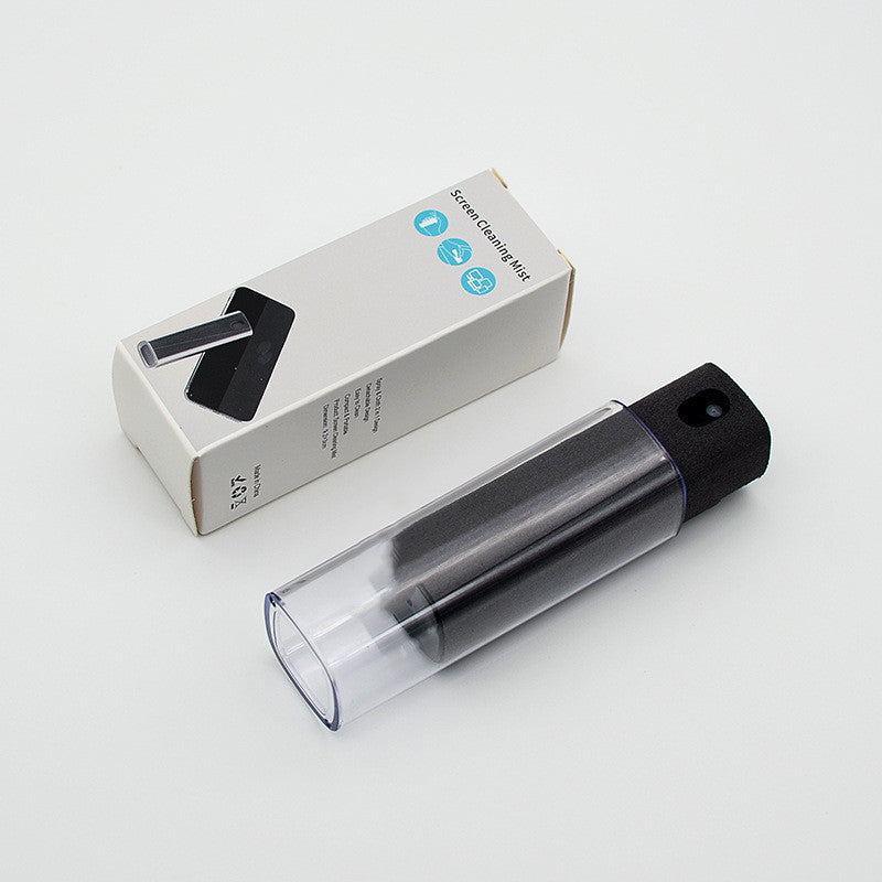 Clear spray bottle with black cap and packaging on a light gray background