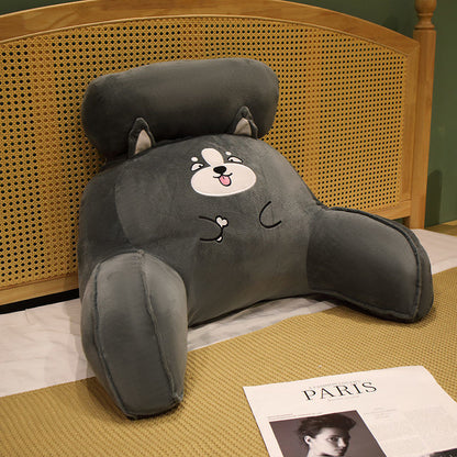 Gray cartoon dog-shaped backrest pillow on a bed with a wicker headboard.