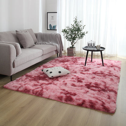 Living room with a pink rug, gray sofa, and small table with decor items.
