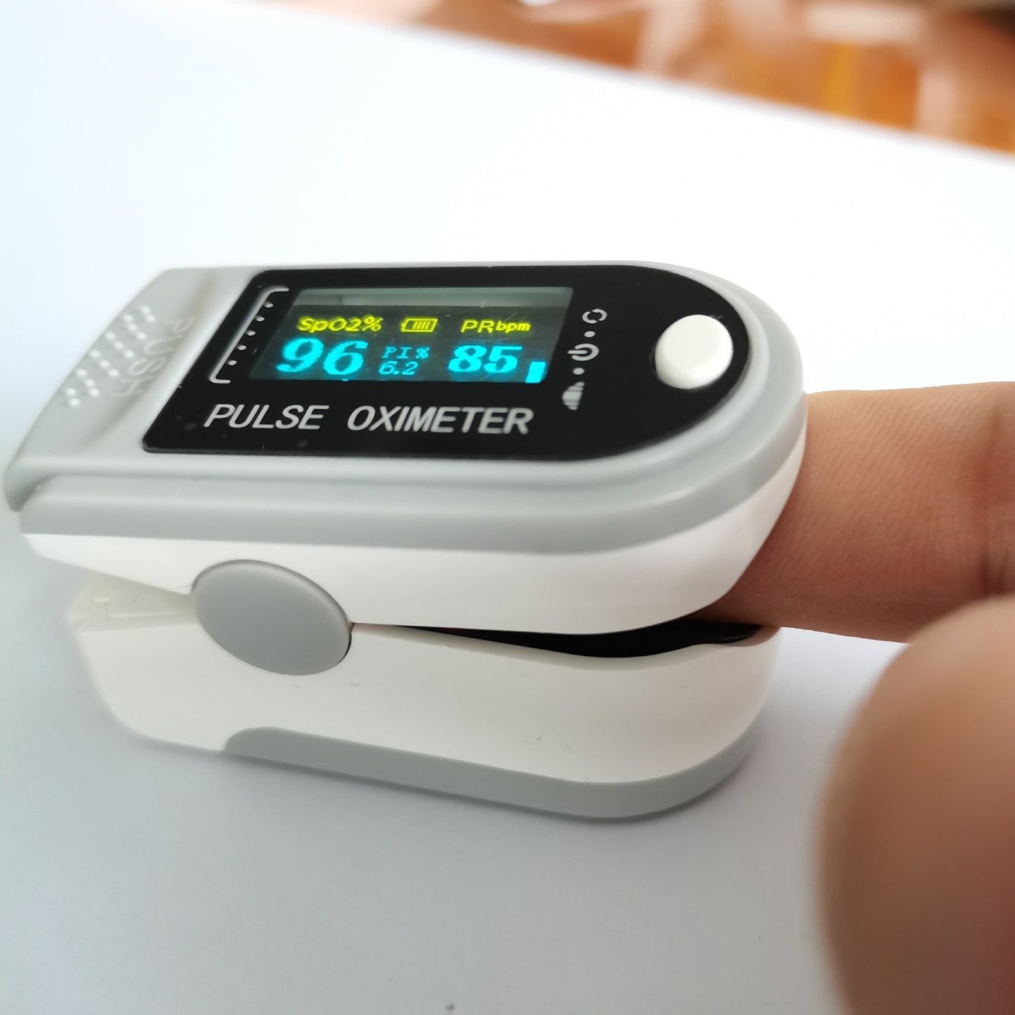 Pulse oximeter on a finger with digital display showing heart rate and oxygen levels.