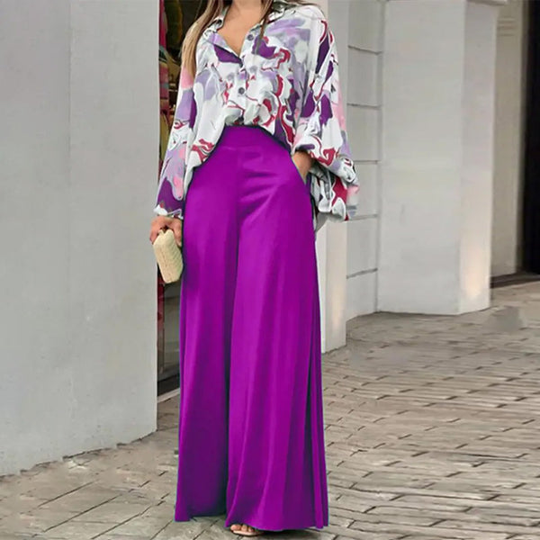 Person wearing a colorful top and purple pants on a sidewalk.