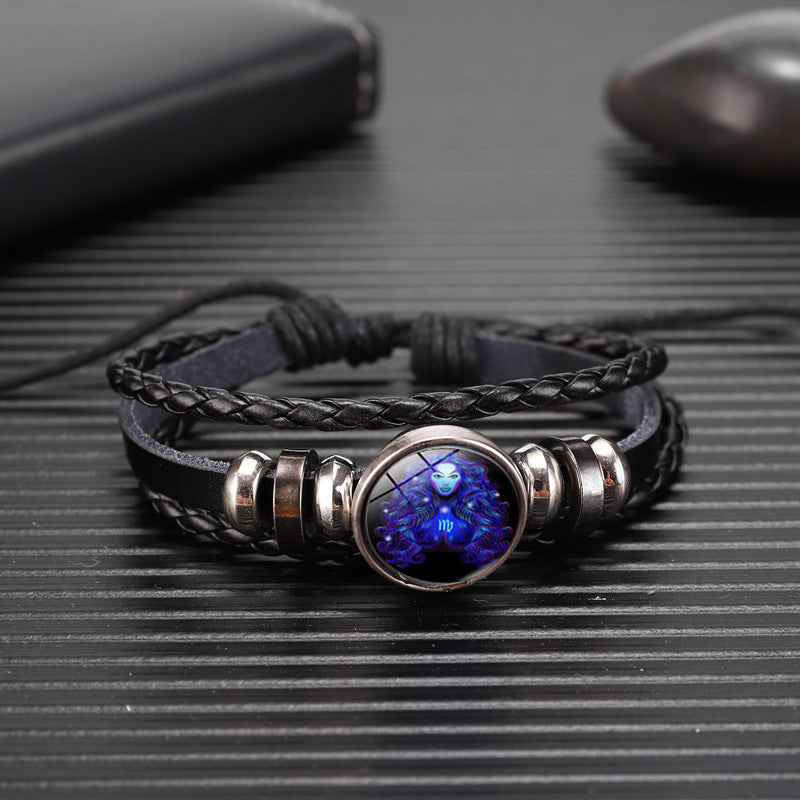 Black braided leather bracelet with a blue stone on a textured surface