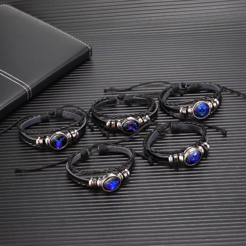Set of black leather bracelets with blue stones on a textured black surface