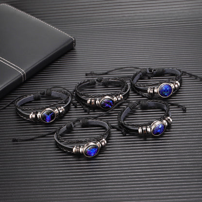 Set of black leather bracelets with blue stones on a textured black surface