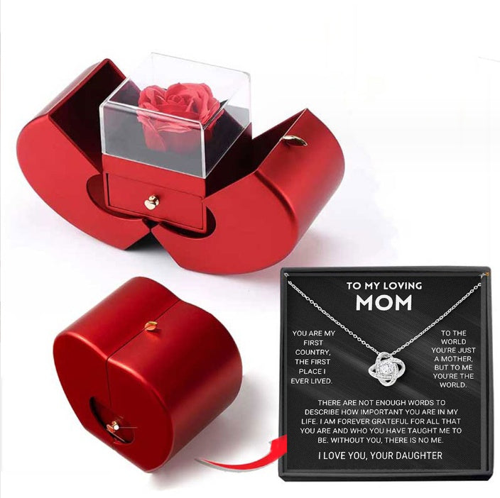 Red jewelry box with a rose, necklace with message card, and red ribbon on a white background