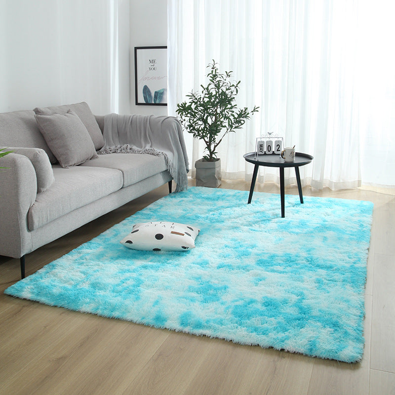 Living room with a blue and white fluffy rug, gray sofa, and small table with decor items.