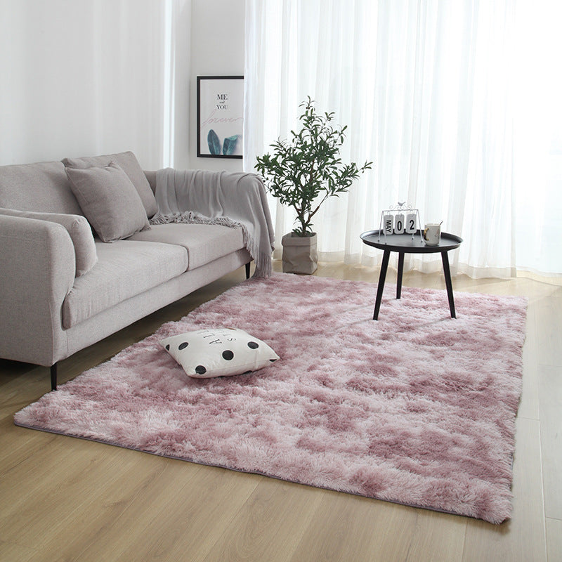 Living room with a pink rug, gray sofa, and decorative items.