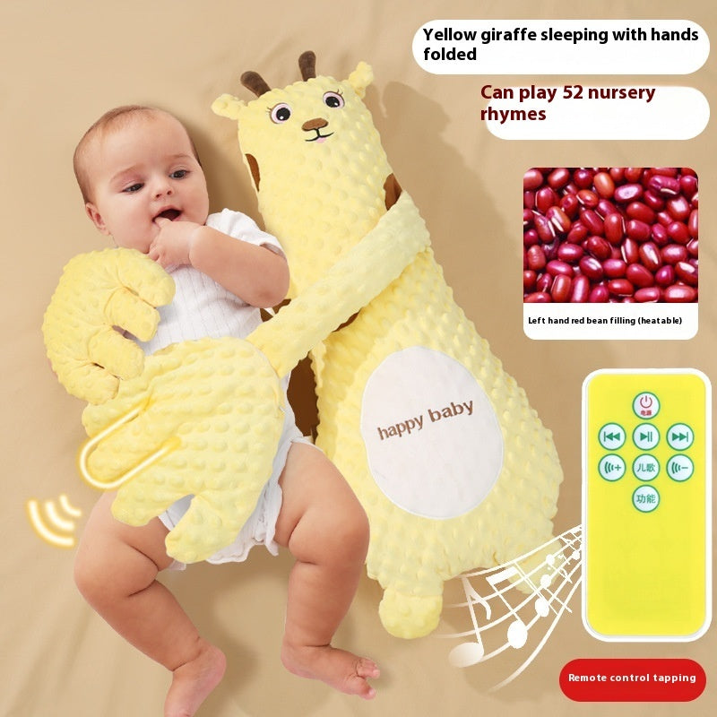 Baby holding a yellow giraffe plush toy with remote control, sitting on a beige surface.