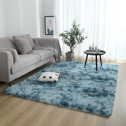 Living room with a blue rug, gray sofa, and a small table with decor items.