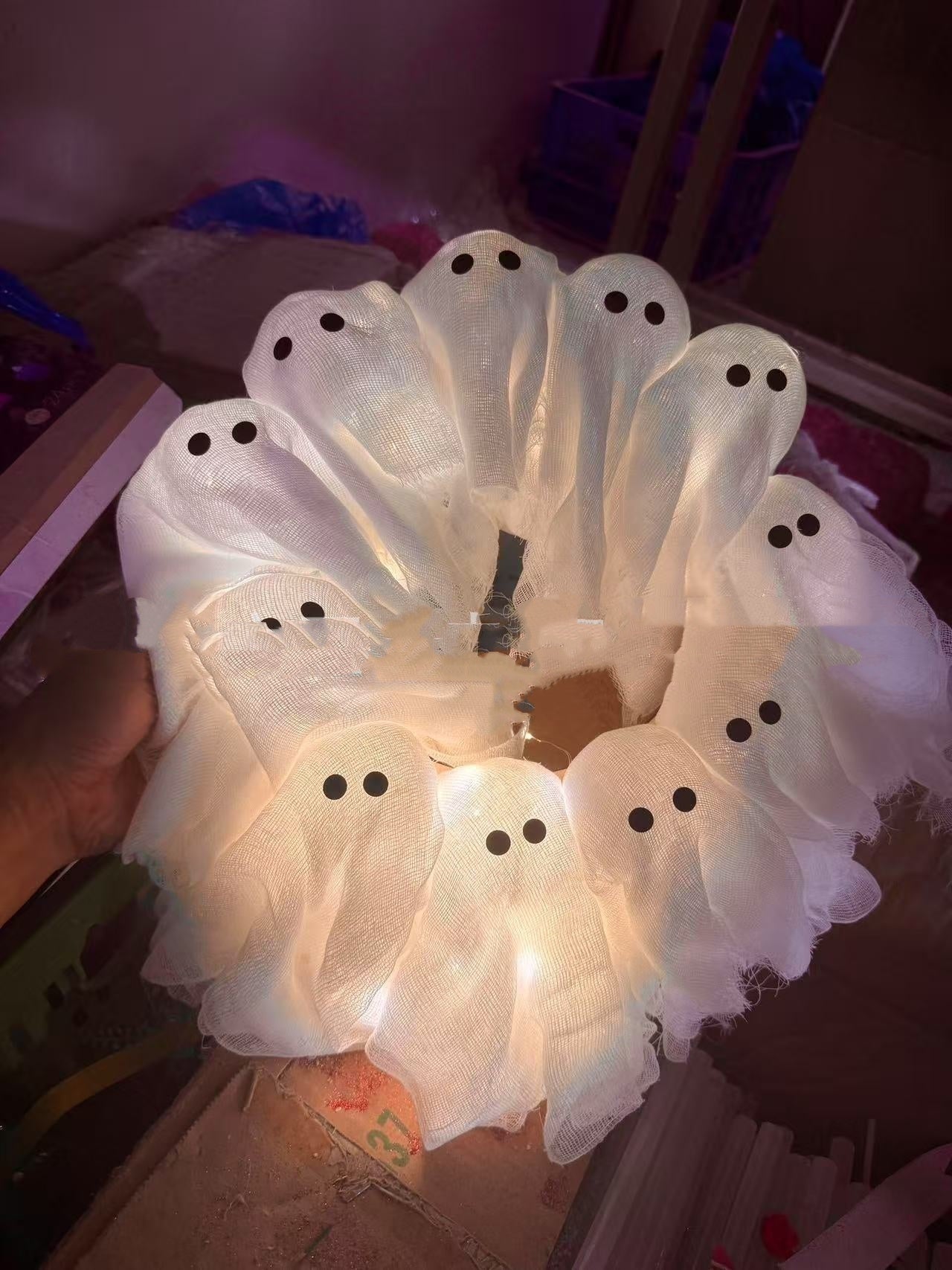 Decorative wreath with ghost figures on a plain background