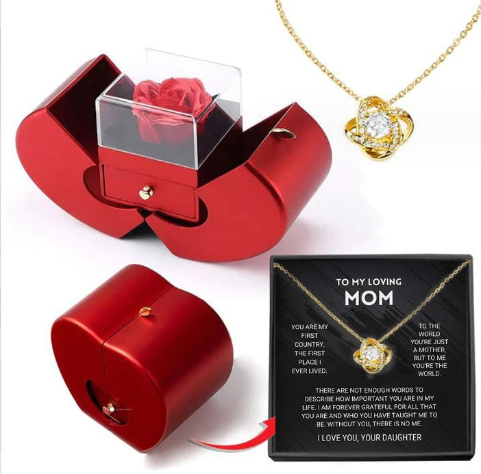 Red jewelry box with a rose, gold necklace with heart pendant, and card for mom on a white background
