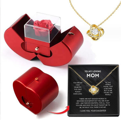 Red jewelry box with a rose, gold necklace with heart pendant, and card for mom on a white background