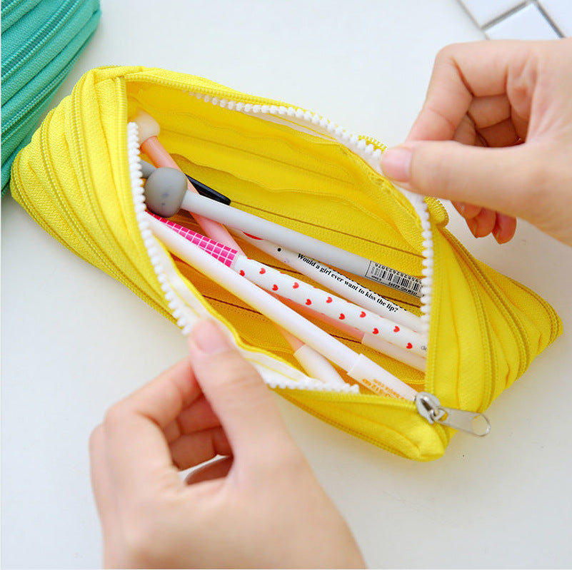 Yellow pencil case with stationery items being accessed by hands on a white background