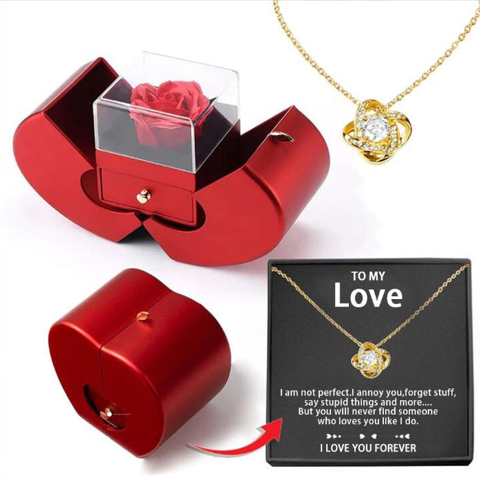 Red gift box with a rose, gold necklace with heart pendant, and black card with text on a white background.
